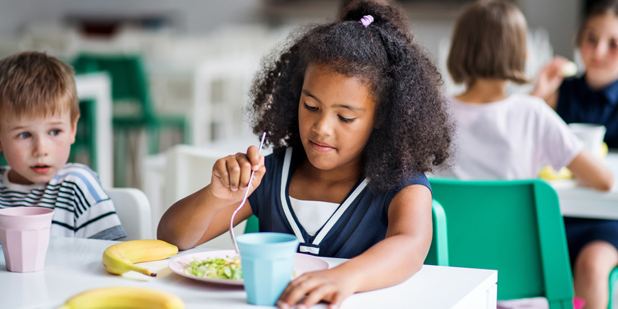 Petite fille dégustant une salade à la cantine