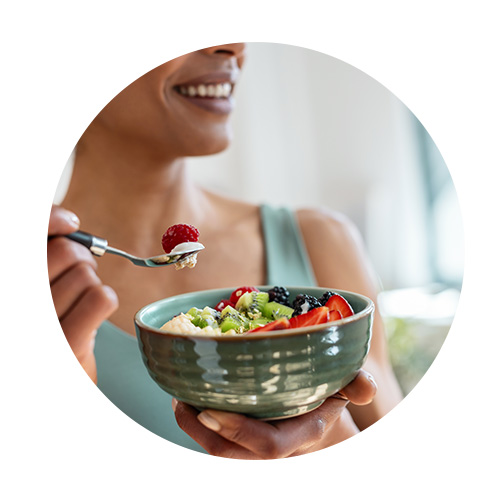 Femme qui mange un bowl contenant du fromage blanc et divers fruits récupération sportive alimentation - Aprifel